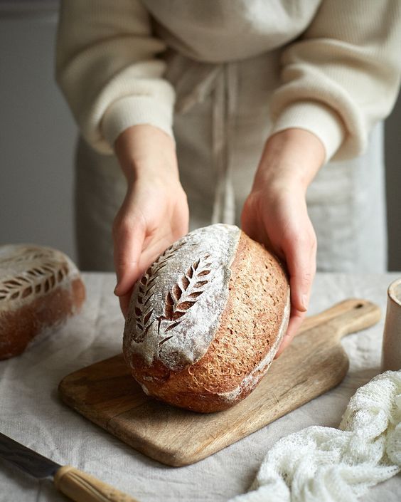 A finished sourdough loaf being presented on a wooden board