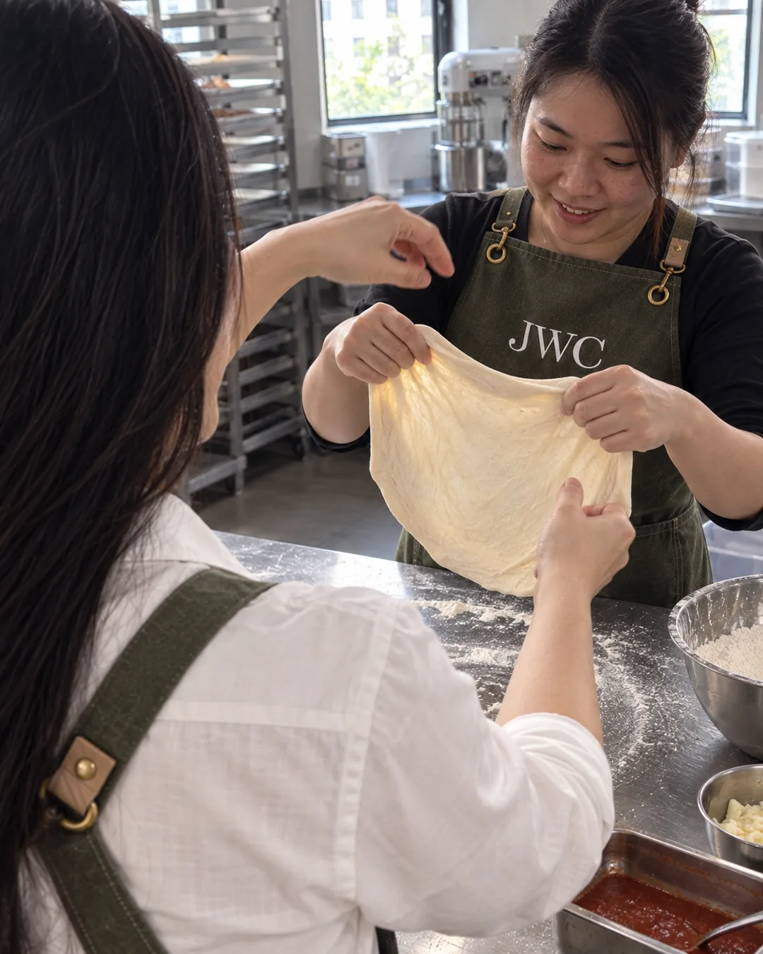 A learner stretching dough as Siew Wei guides from the foreground